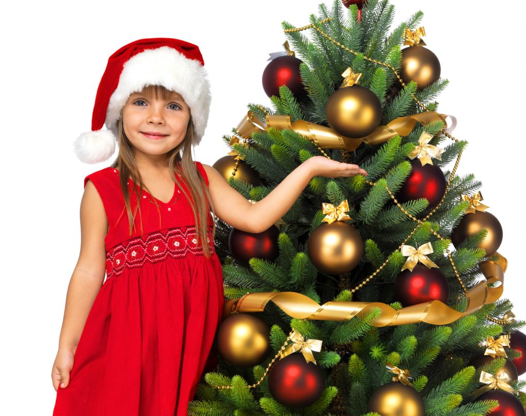 Pretty little girl smiling with present near the Christmas tree