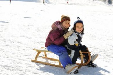 Happy children sledding on snow, mountaint park
