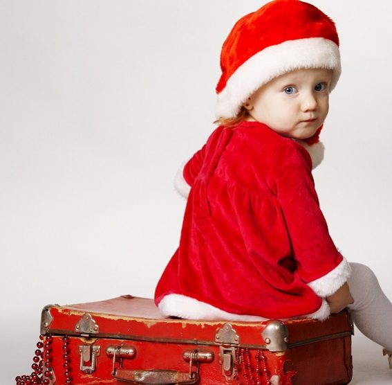 girl with Santa cap sitting on suitcase